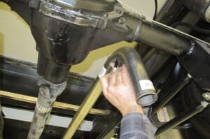 Mechanic checking tailpipe for exhaust blockage causing smell in car